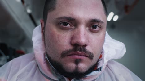 bearded paramedic in hazmat suit looking at camera tired bearded male doctor in hazmat suit looking at camera while working difficult shift in ambulance during pandemic