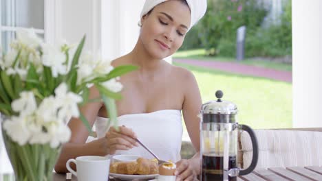 una mujer joven y bonita tomando el desayuno en un patio.