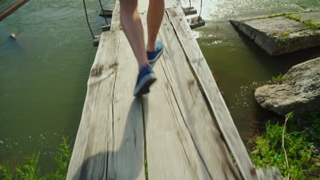 men's legs go along a narrow wooden bridge over the precipice and a mountain river overcome the fear