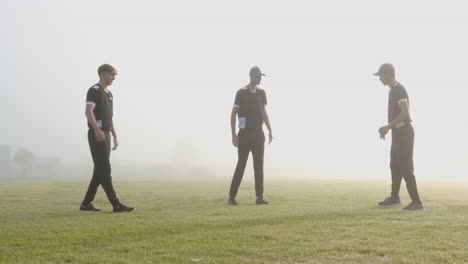 male cricket players wearing black uniforms practicing cricket on pitch