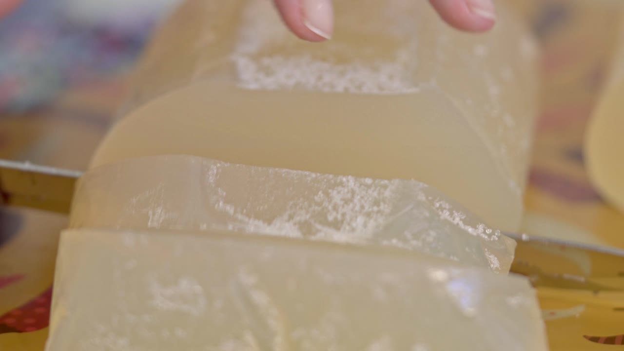 Close-up of a Woman's Hand Cutting Glycerin Soap Base into Large Pieces for Handmade Soap