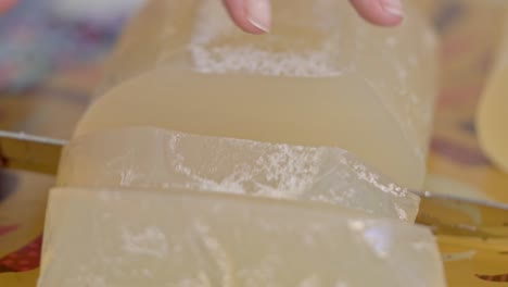 Close-up of a Woman&#039;s Hand Cutting Glycerin Soap Base into Large Pieces for Handmade Soap