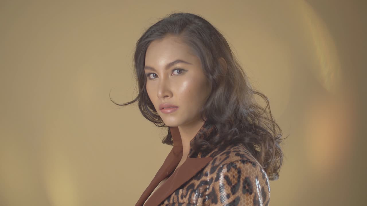 modelo asiático posando para disparos en la cabeza contra un fondo beige - fuga de luz anamórfica