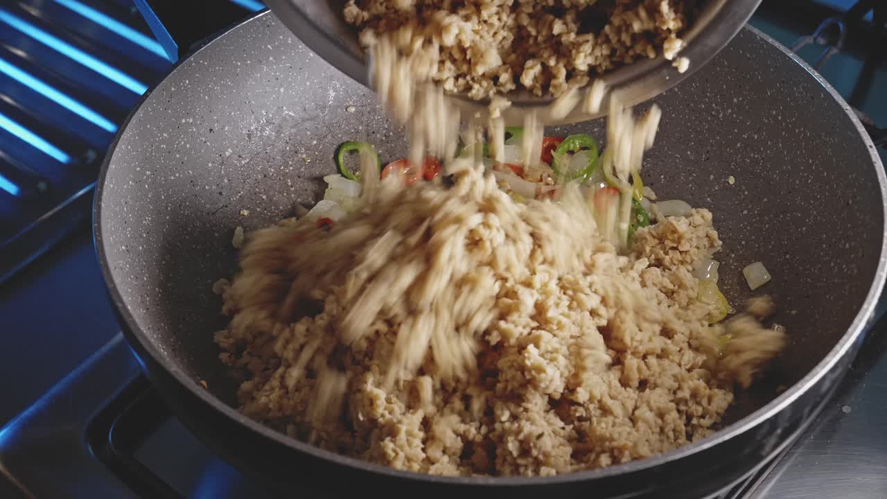agregando verduras texturizadas a una olla llena de ingredientes vegetales para un plato vegetariano, vista de cerca