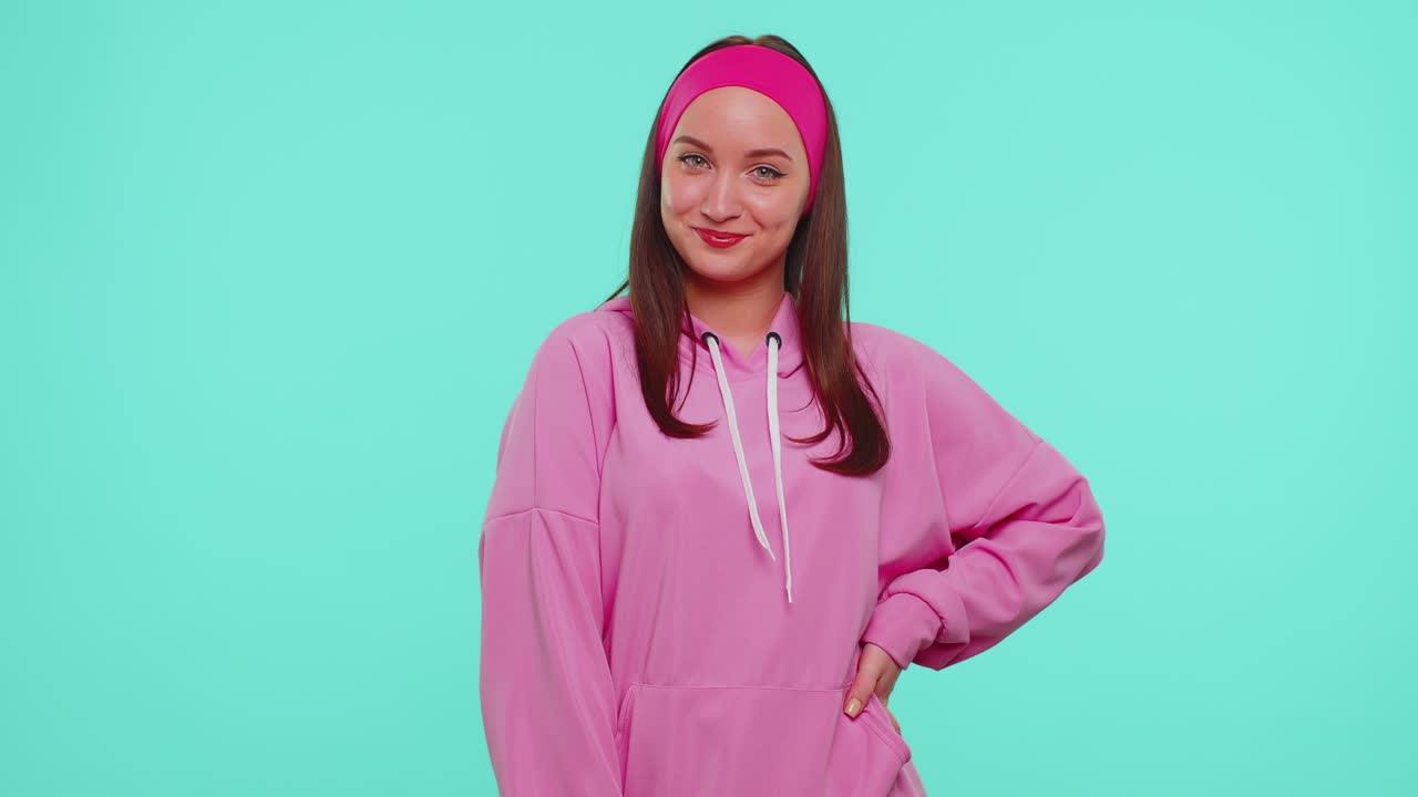 Fröhliche, schöne Teenager-Studentin, Modemodell in rosa Hoodie, lächelnd und in die Kamera schauend