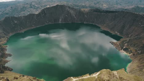 quilotoa volcanic crater lagoon with turquoise waters in ecuador - aerial drone shot