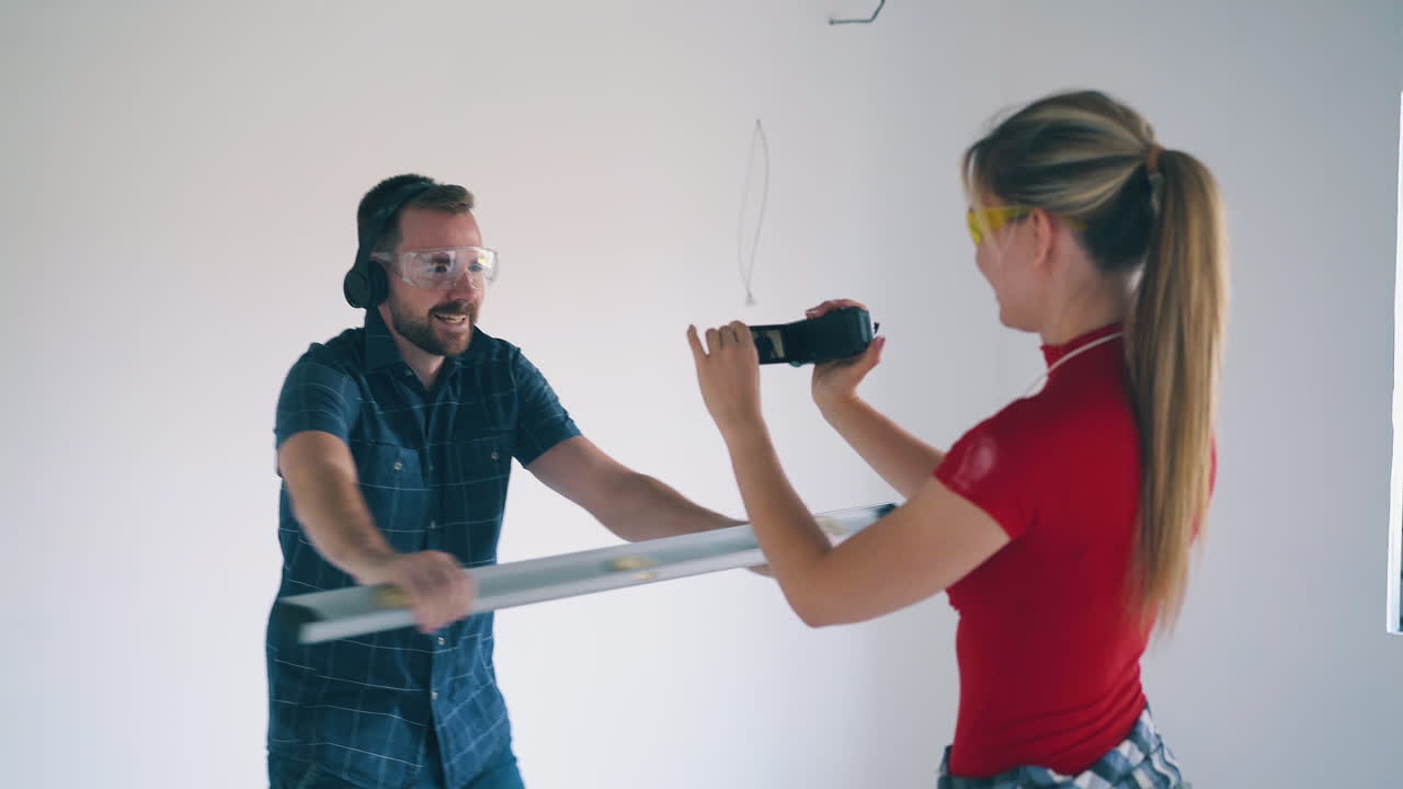 mujer dispara a su novio bailando con el nivel cerca de la pared blanca
