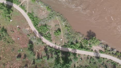 Draufsicht-Auf-Die-Starke-Schlammige-Strömung-Des-Colorado-River-In-Moab-Mit-Einer-Parallelen-Straße