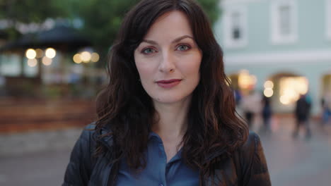 close up portrait of elegant woman in city  looking pensive thoughtful at camera on urban evening background