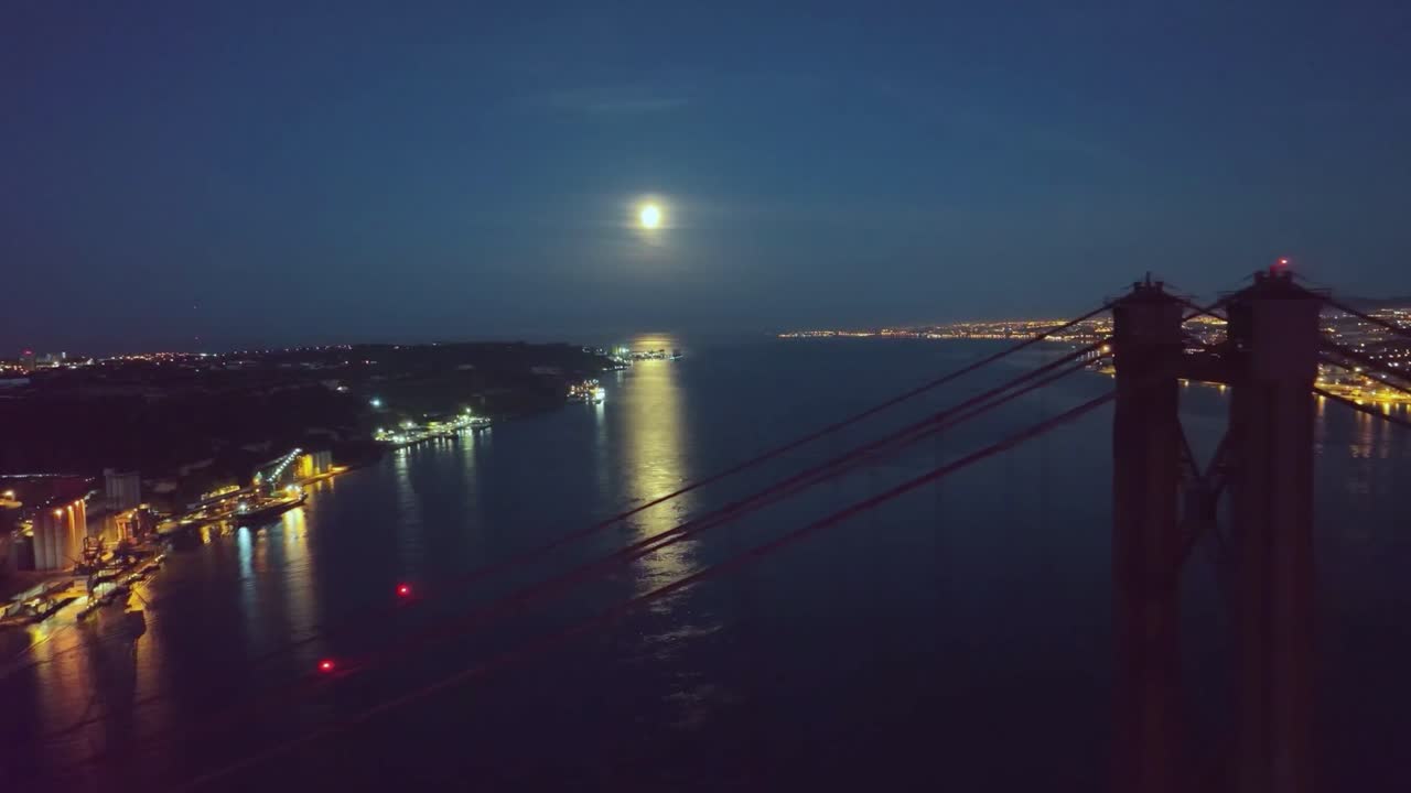 Droneoptagelse af månen og toppen af broen, Ponte 25 Abril, i Lissabon