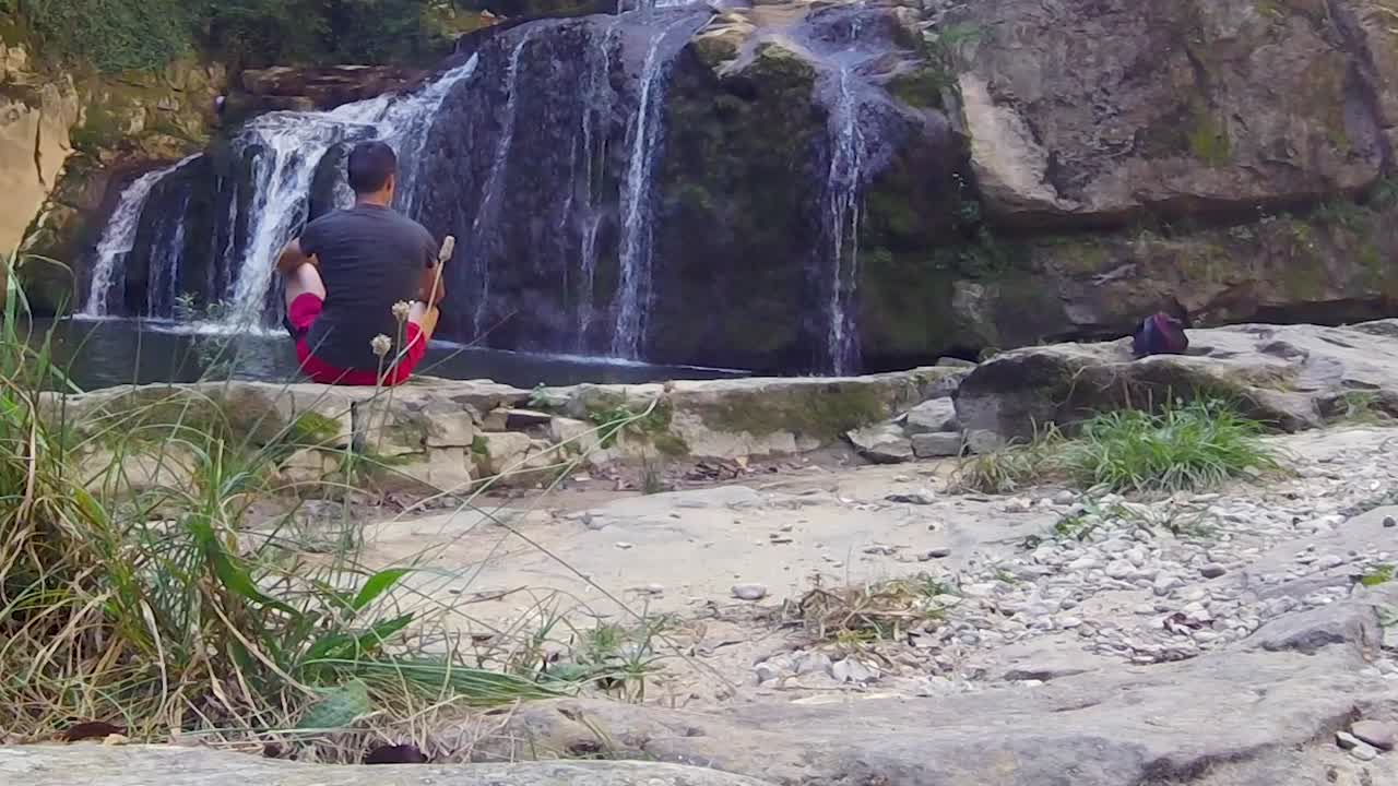 joven relajándose cerca de la majestuosa cascada, toma en cámara lenta