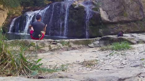 young person relaxing near majestic waterfall, back slow motion shot