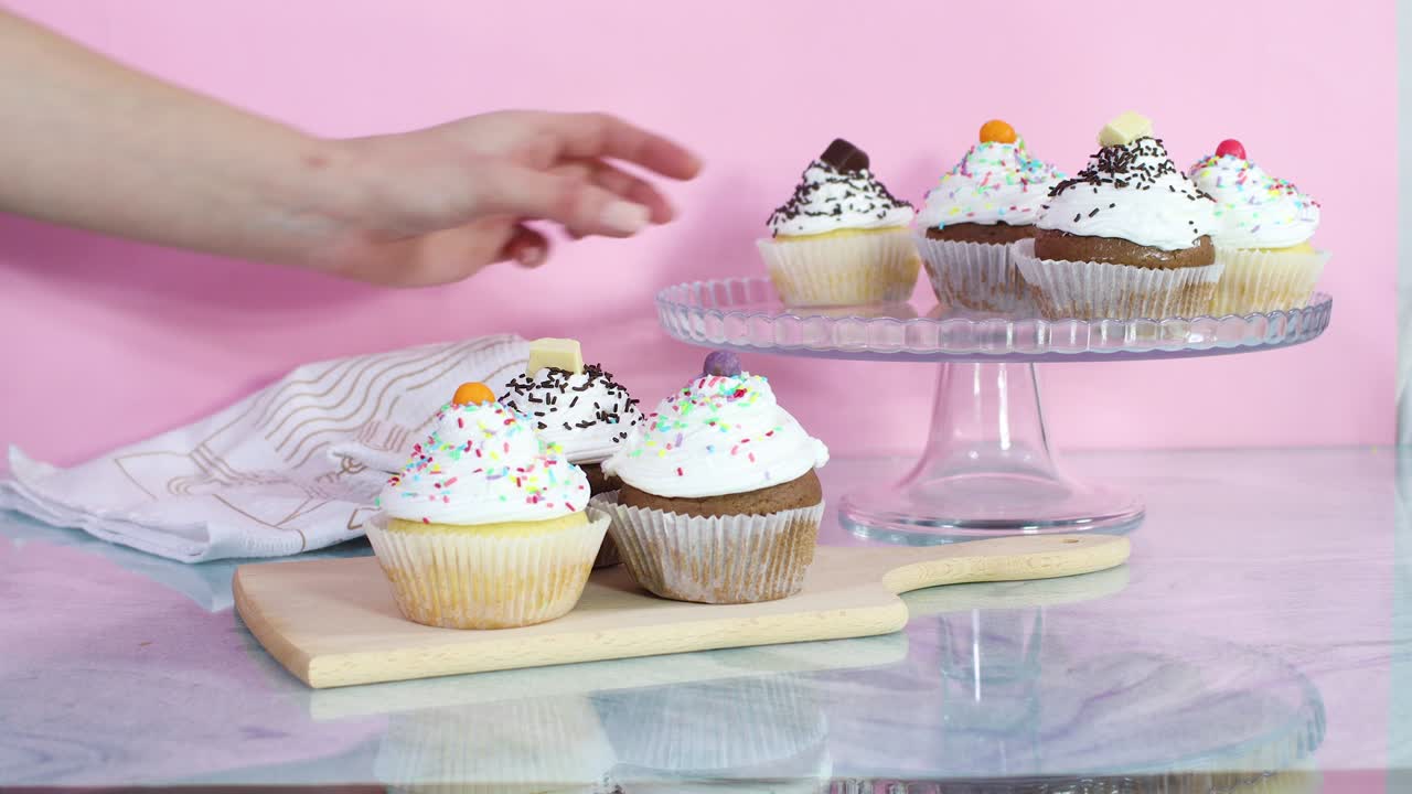 Serving delicious cup cakes from cutting board on crystal plate for party