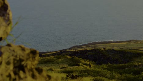 Shot-from-behind-a-rocky-Hawaiian-landscape-revealing-the-Pacific-ocean-at-sunset