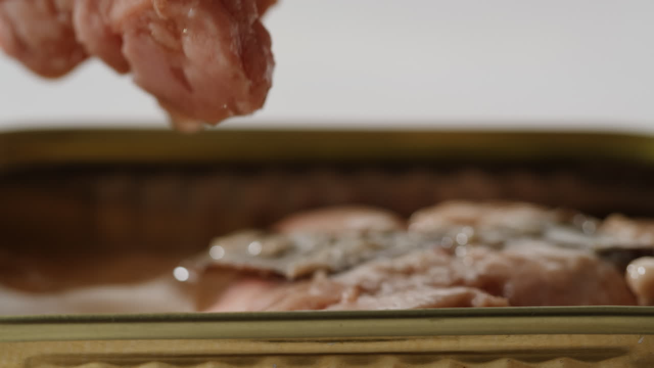 Smoked cod liver in oil in open tin can with fresh greens on wooden table. Seafoods delicacy. High quality 4k footage