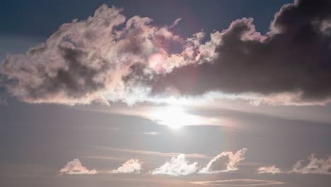 amazing nature sky of dramatic clouds with lens flare in a blue sky as a fluffy white cloud approaches and obscures it sending light rays and shadows from the cloud time lapse nature background