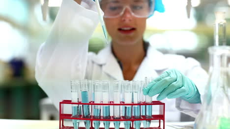 hermosa estudiante de ciencias usando pipeta para llenar tubos de ensayo