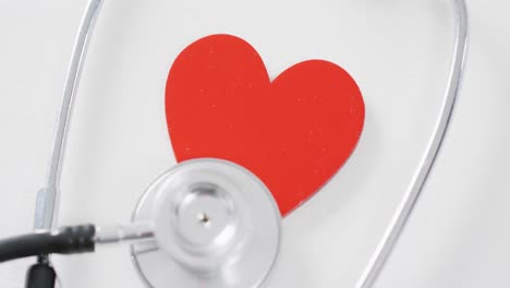 Video-of-close-up-of-heart-and-stethoscope-on-white-background