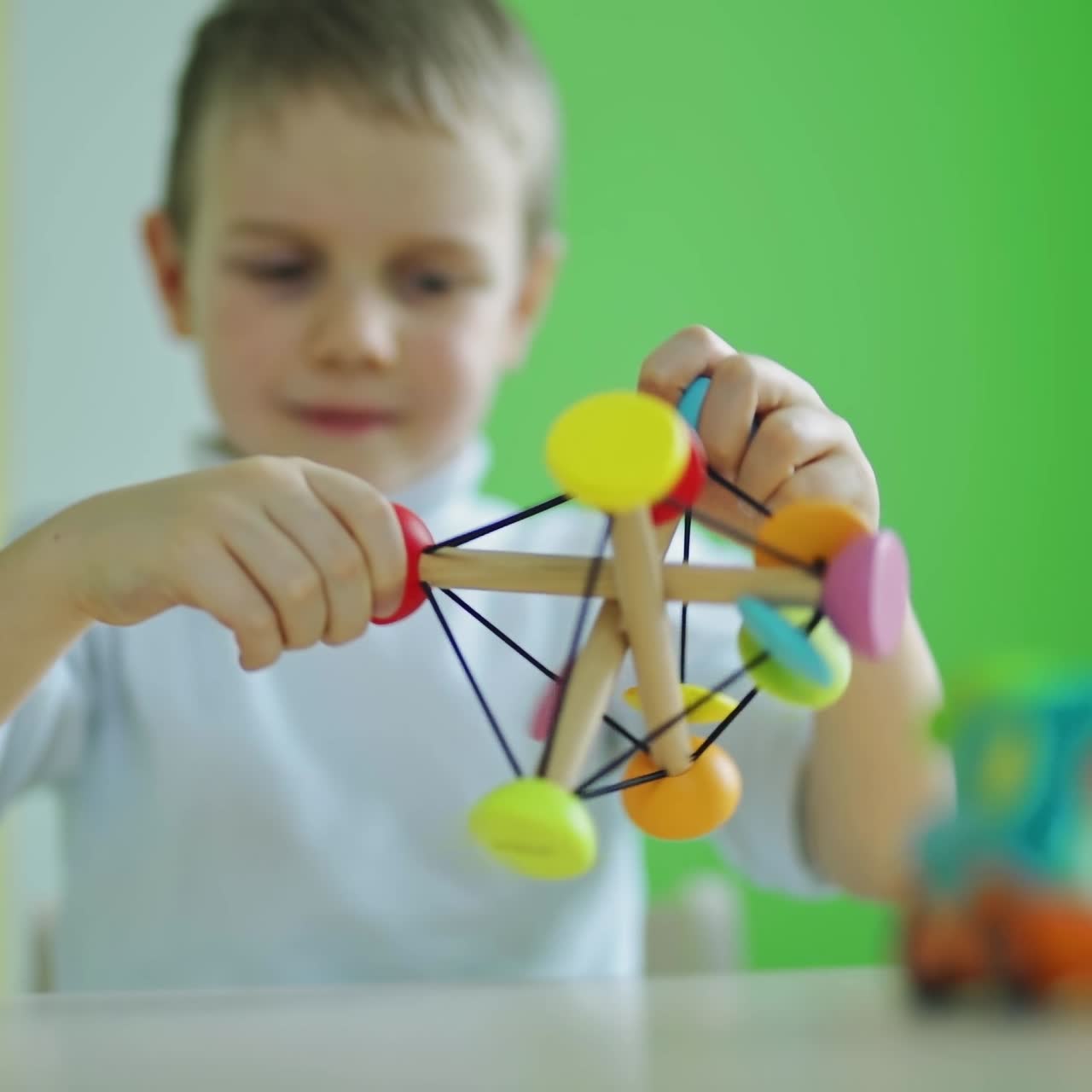 Bright toy in kid's hands. Little boy playing with wooden toy in the room. Adorable child playing with a colorful toy. Childhood concept.