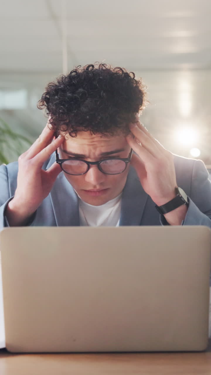 Uomo d'affari stressato con mal di testa che lavora al laptop in ufficio