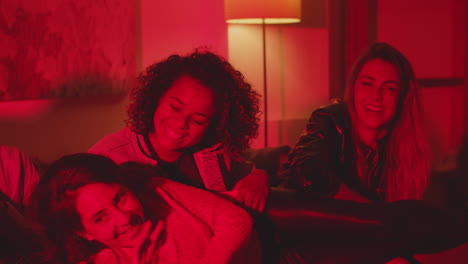 chica feliz acostada en las rodillas de sus amigas en la fiesta de la casa de la noche