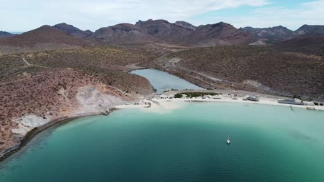 Aerial-dolly-shot-of-Playa-Pichilingue-near-the-ferry-and-cruise-port-of-La-Paz,-Baja-California-Sur,-Mexico-with-sandy-beach,-idyllic-coastline-and-majestic-mountains-in-the-background