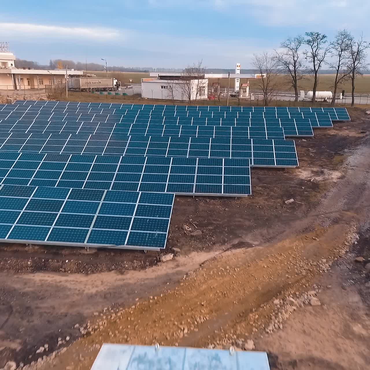 Blue solar panels on the field. Big photovoltaic panels receiving ecological energy from the sun. Modern solar power plant near the highway. Motion camera back.
