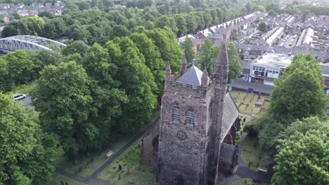 Aerial-view-above-rural-English-town-woodland-countryside-idyllic-church-bell-tower-and-graveyard