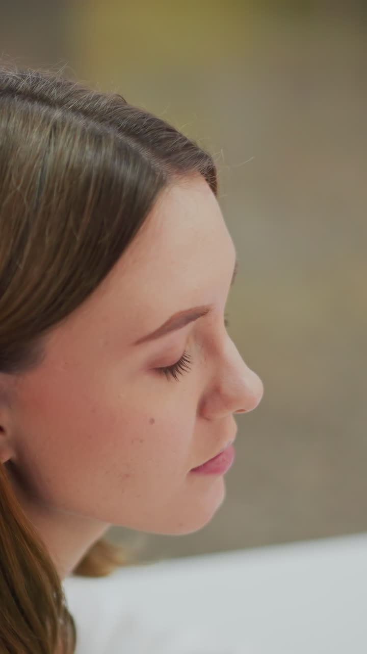 primer plano de una mujer joven con expresión pensativa mirando hacia adelante en un ambiente interior vibrante con un sutil desenfoque de fondo colorido y iluminación suave