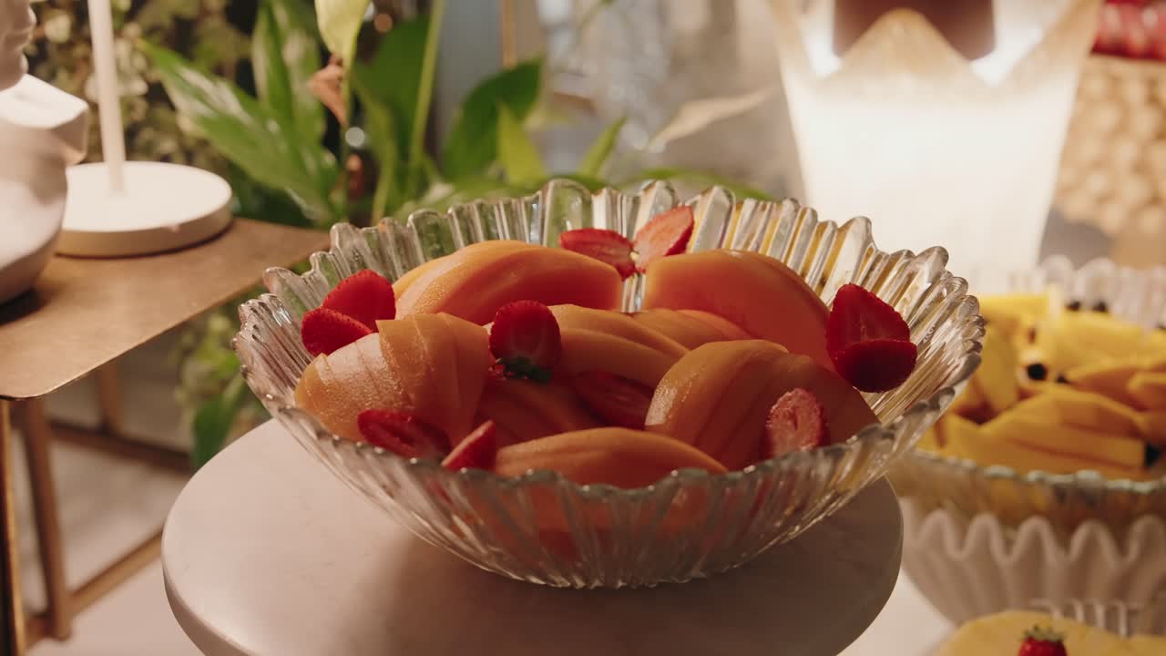 Fuente con rodajas de melón y fresas expuesta en una mesa de postres decorada para eventos