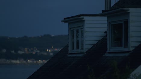 house roof windows at night with city lights in the background