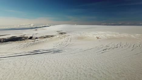 aerial landscape view of many cracks on the ice surface of an icelandic glacier, over the clouds, on a bright sunny day