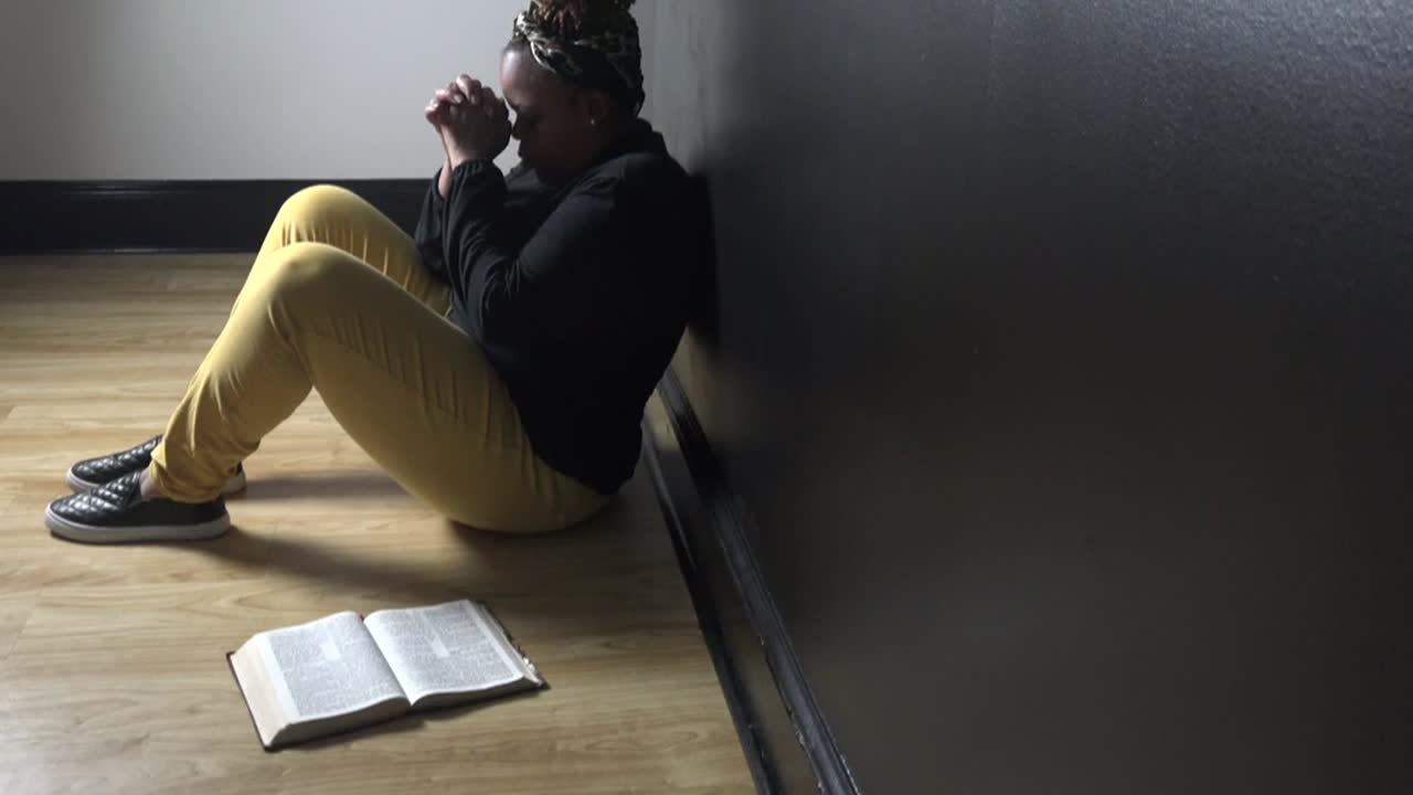 zoom lento de una mujer africana negra rezando en el interior, sintiéndose triste pero esperanzada