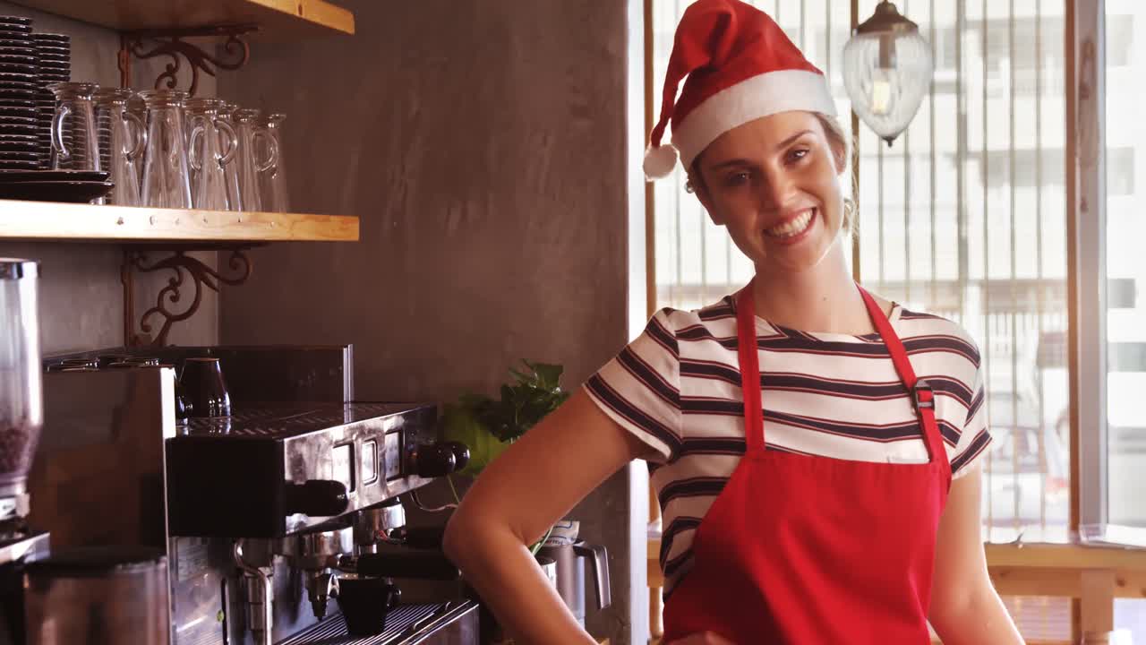 산타 모자 에 서 있는 웨이트리스 가  ⁇  에 손 을  ⁇ 고 있다