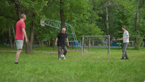 grandfather, father, and son enjoy a day outdoors playing football on a grassy field near a goalpost, surrounded by trees