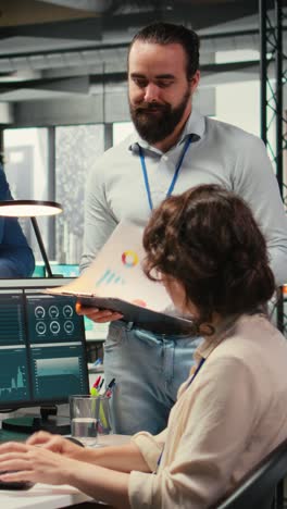 vertical video multiethnic work team consulting each other in completing monthly reports