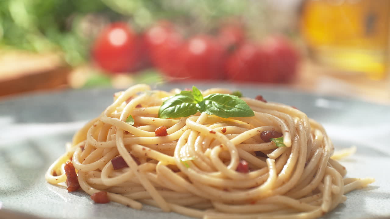 레스토랑에서 밝은 접시에 제공 된 신선하게 조리 된 스파게티 카르보나라에 핀세저로 바실리 잎을 넣는 것, 리 아웃, 느린 동작