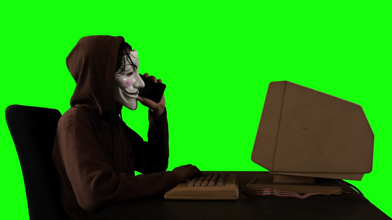 hacker enmascarado hablando con su víctima por teléfono