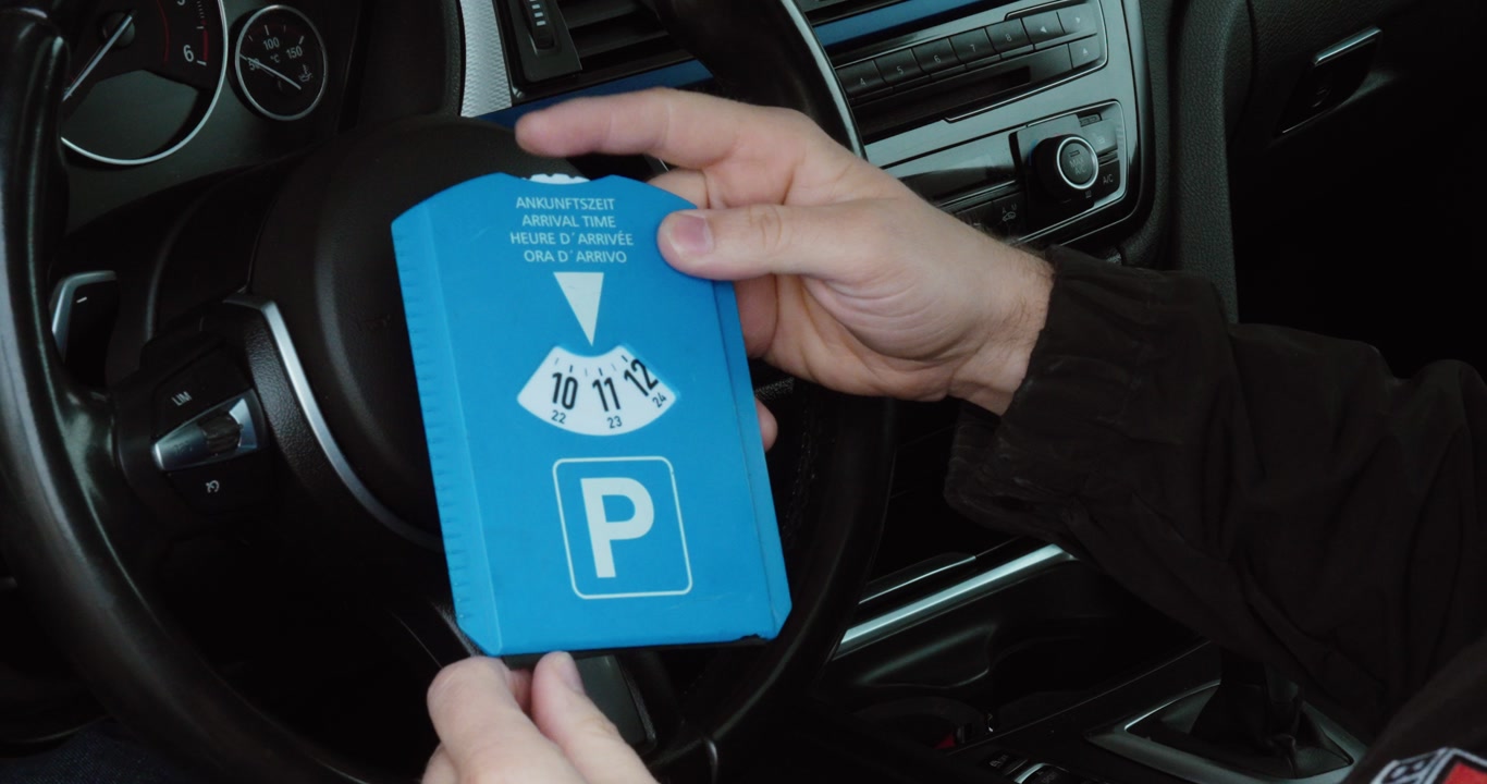 Close-up of a person setting a parking disc inside a car. Concept of parking regulation, time control and driving routine.