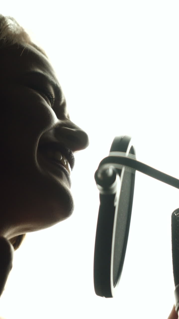 Close-up of girl in headphones singing a song. Professional recording studio Vertical video