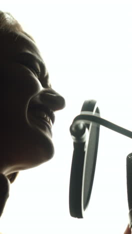 close-up of girl in headphones singing a song. professional recording studio vertical video