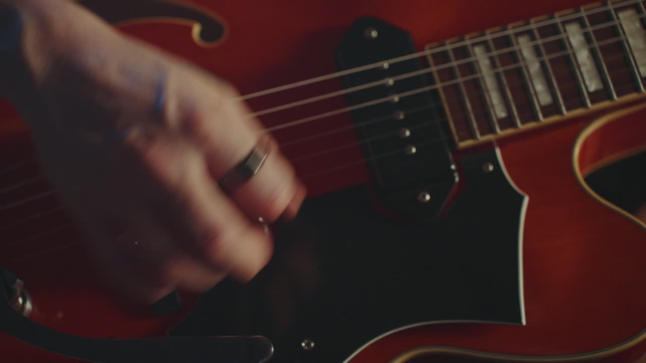 Primo piano di una mano che suona una chitarra rossa
