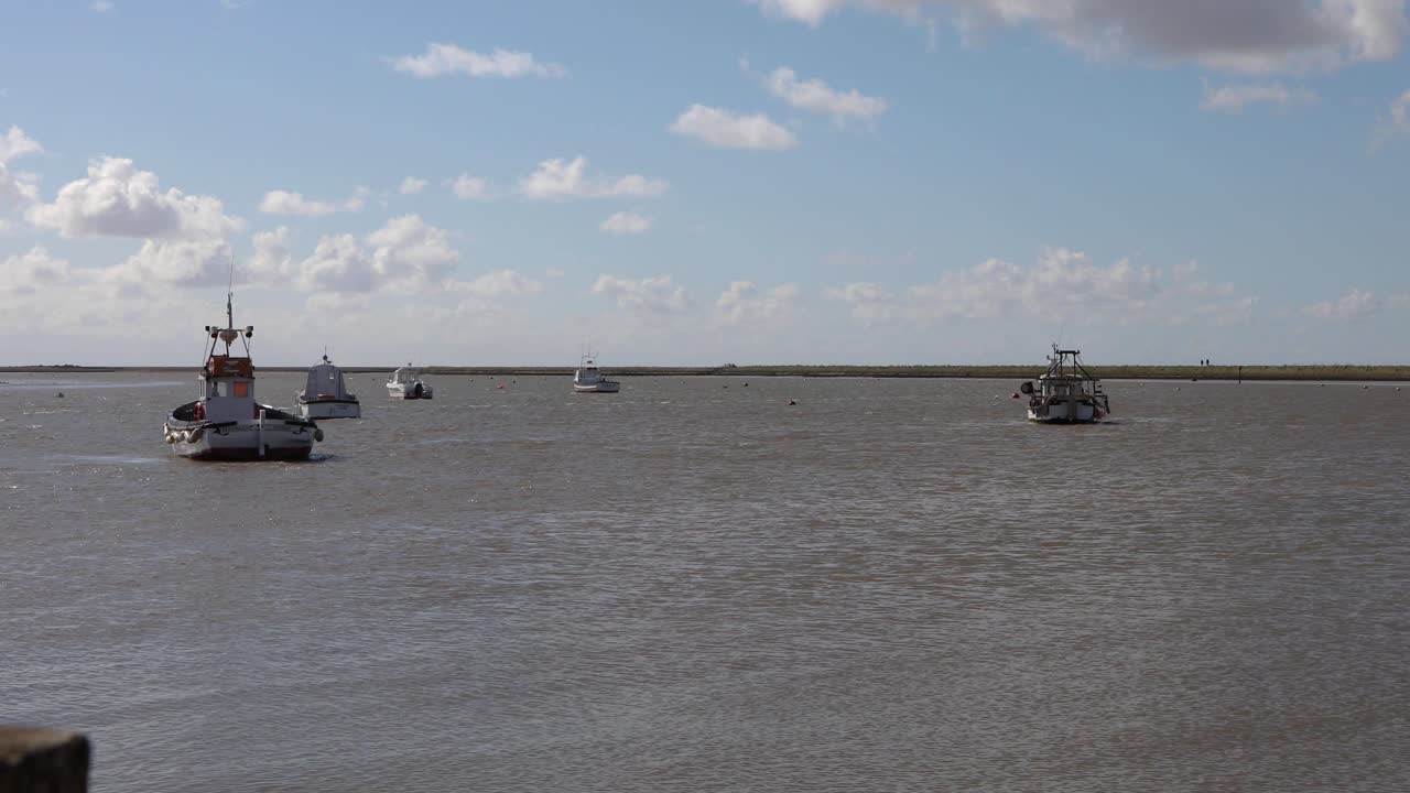 조수가 영국 서포크 해안의 오포드 강어귀로 굴러갈 때 게으른 파도 위에서 위아래로 흔들리는 어선