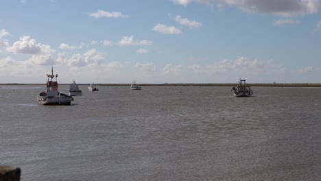 barcos de pesca subiendo y bajando sobre las olas perezosas mientras la marea sube hacia el estuario de orford en la costa de suffolk, reino unido