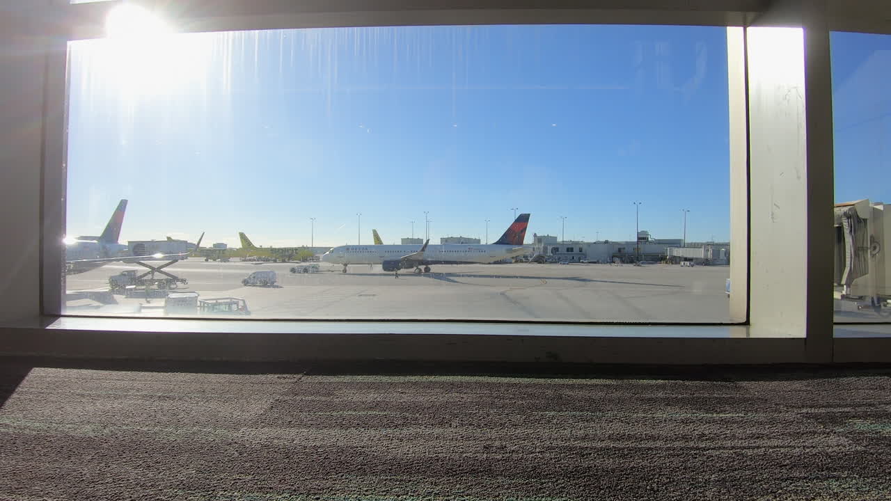 time lapse video of Airplanes parked on the tarmac at Miami international airport, Florida, United States of America, are seen through the window of the terminal, awaiting departure or arrival