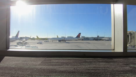 time lapse video of airplanes parked on the tarmac at miami international airport, florida, united states of america, are seen through the window of the terminal, awaiting departure or arrival