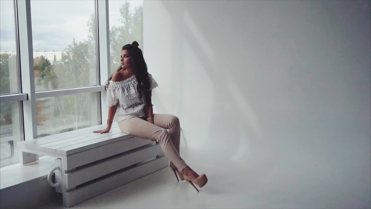 mujer sentada junto a una ventana en un estudio