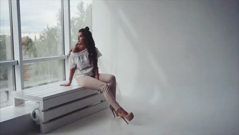 woman sitting by a window in a studio