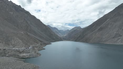 a beautiful view of ali sadpara lake surrounded by the bald karakoram mountains range and clouds cover the sky in the background