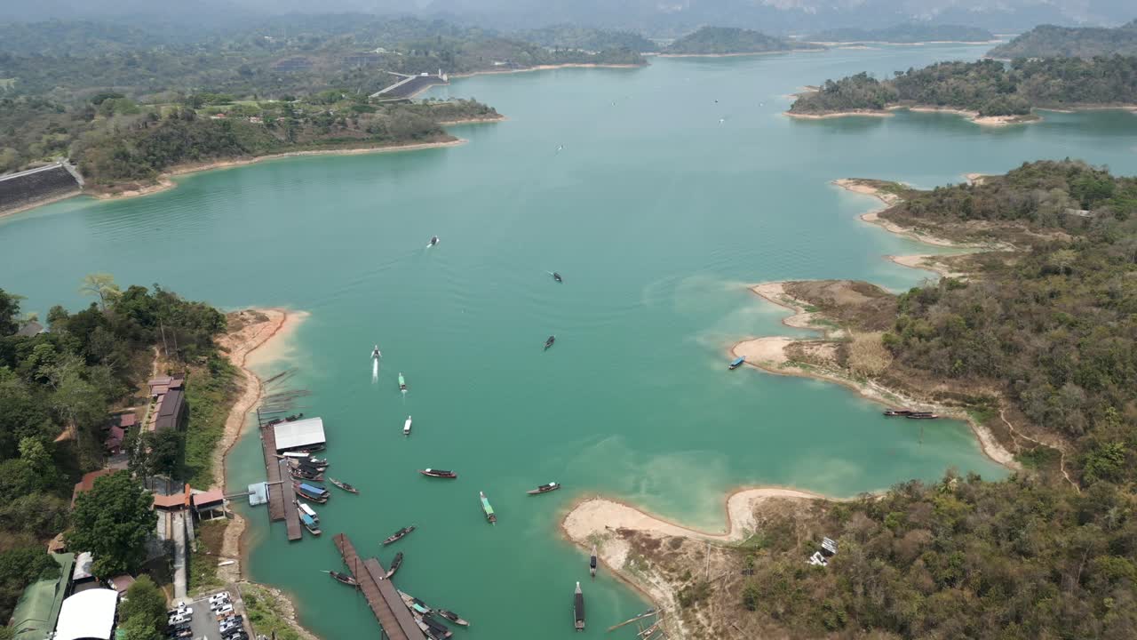 Aerial View of a Turquoise Lake with Boats, Surrounded by Mountains and Forest